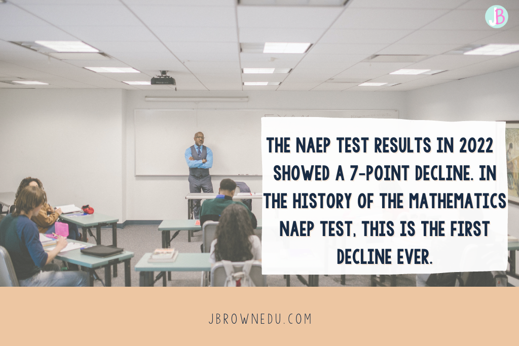 Math growth decline on NAEP test results, black male teacher standing in front of a whiteboard in a classroom of diverse students. The word exam is written on the whiteboard. 